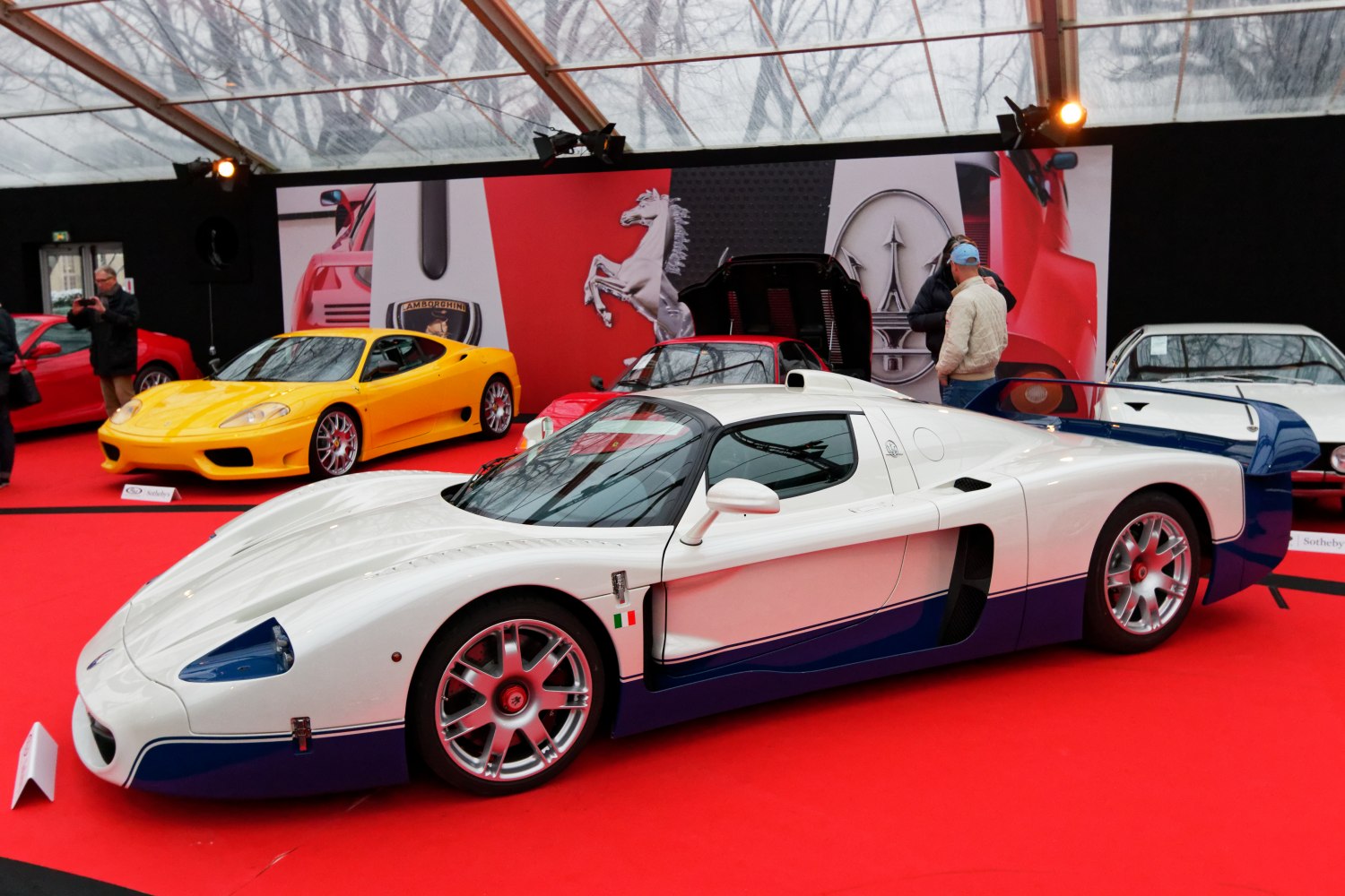 White and blue livery racing supercar with aerodynamic body and large rear wing.