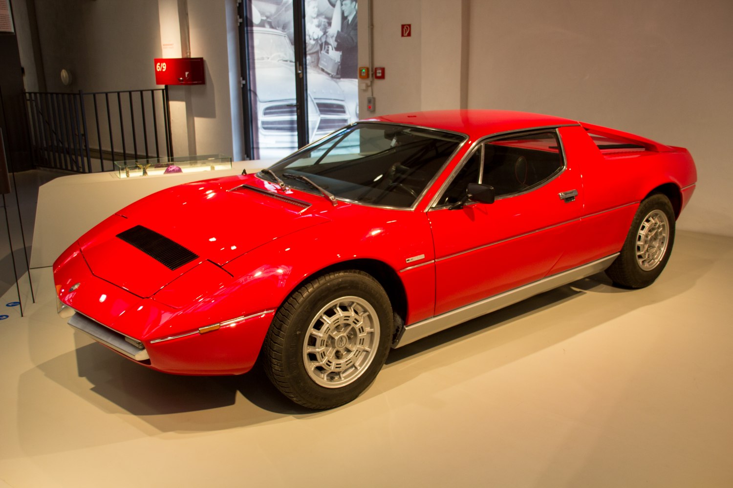 Red mid-engine sports coupe with distinctive alloy wheels and sleek aerodynamic design