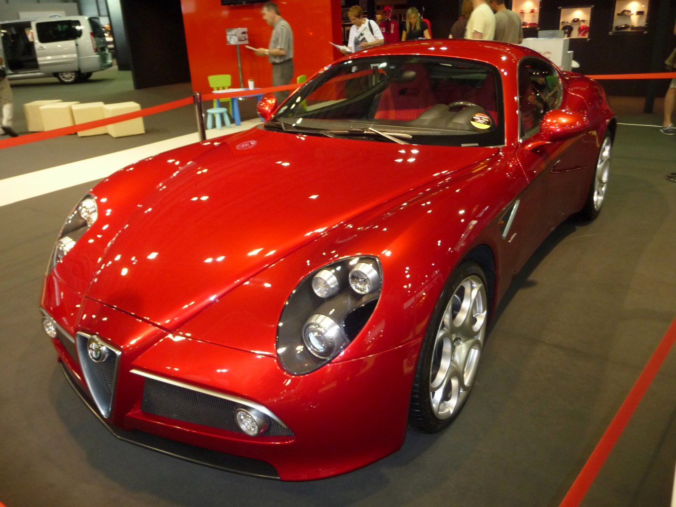 Red sports coupe with quad circular headlights and unique five-hole alloy wheels