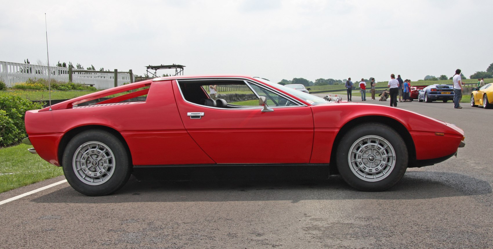 Sleek red classic sports coupe side profile with distinctive alloy wheels