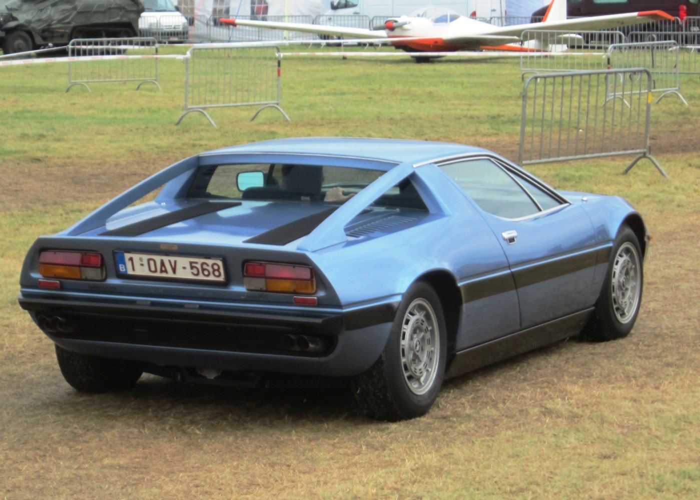 Mid-engine sports coupe rear view with rear louvers and twin exhausts.
