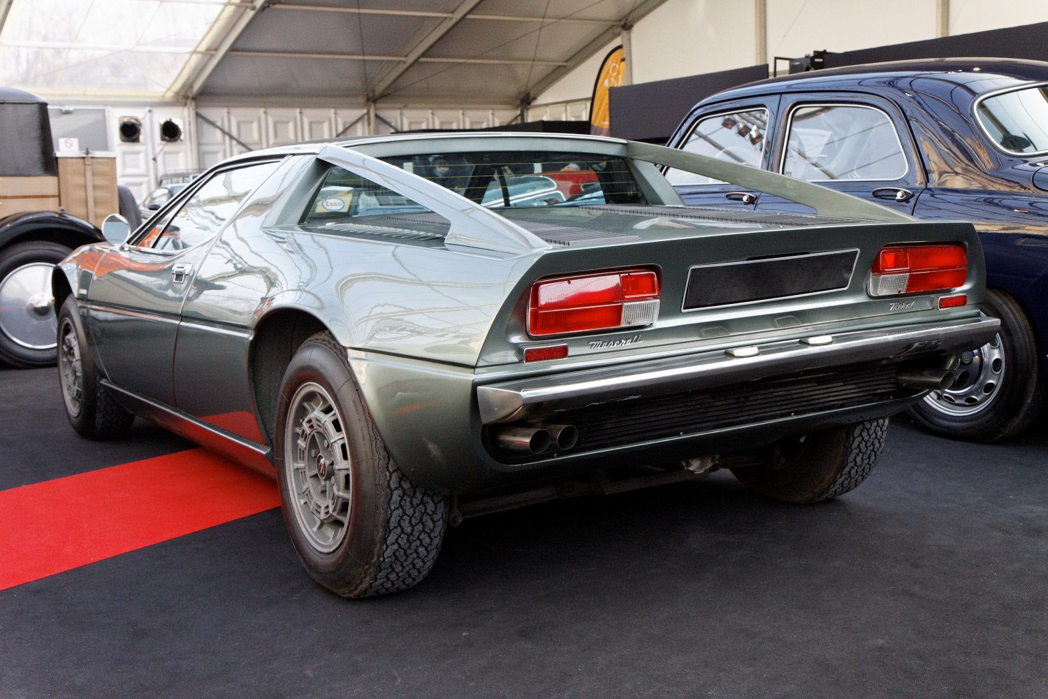 Rear view of vintage sports coupe with louvered rear window and dual exhaust pipes