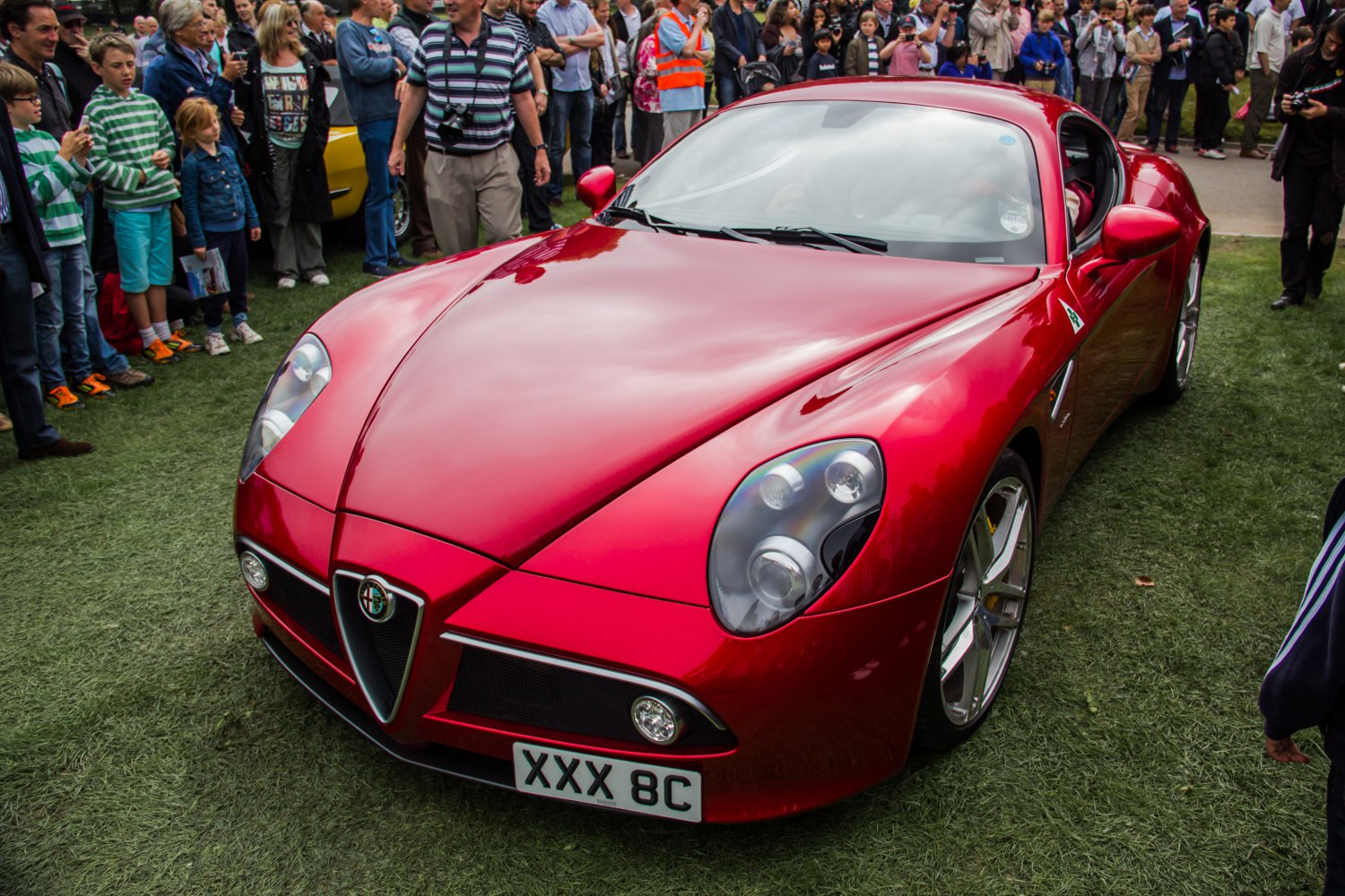 Red sports car front view with distinctive headlights and aerodynamic curves.