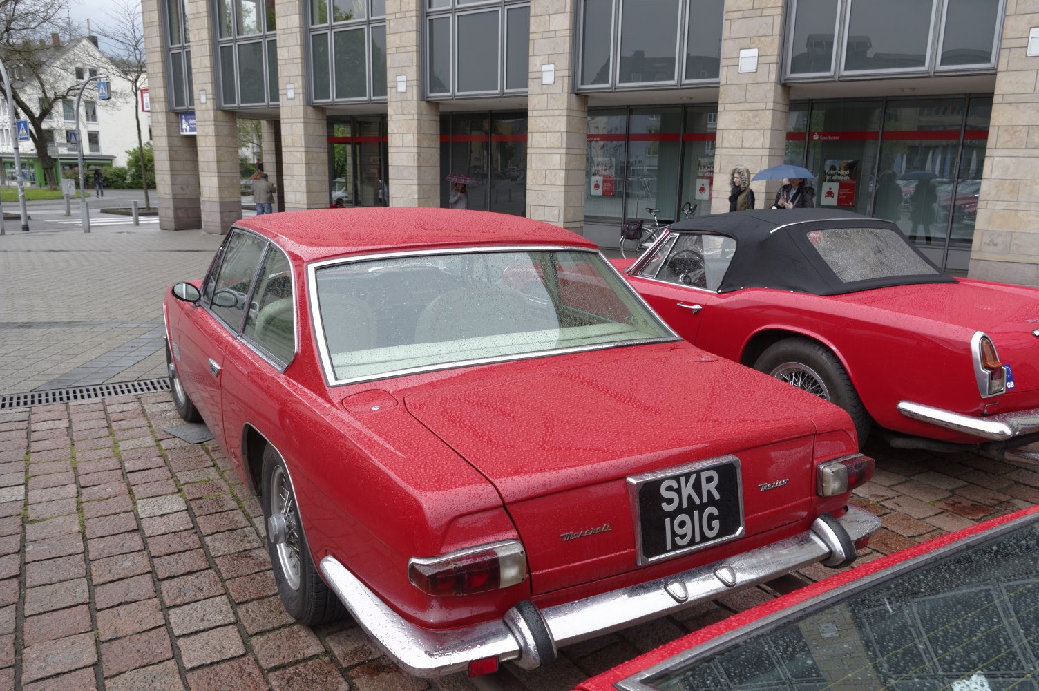 Rear view of a red classic 1960s luxury coupe with chrome bumper and wire wheels