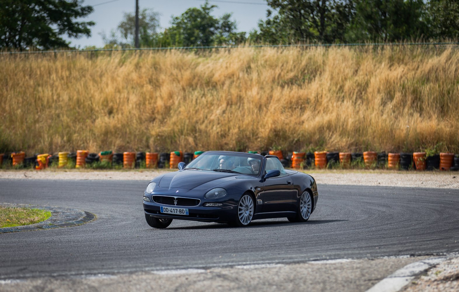 Convertible sports car on racetrack corner with open roof