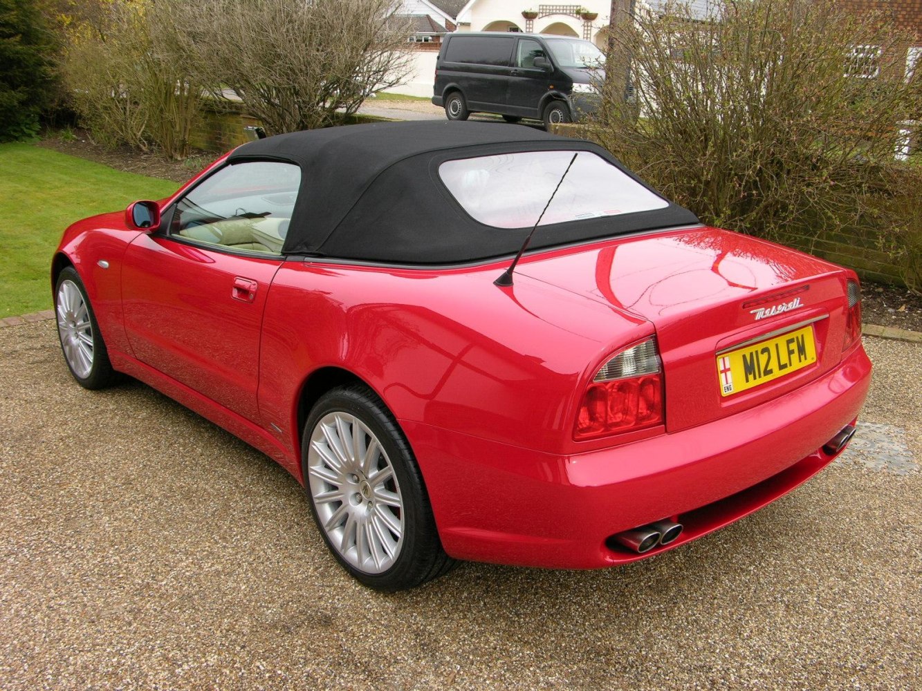 Red convertible with black fabric soft top and dual exhaust pipes