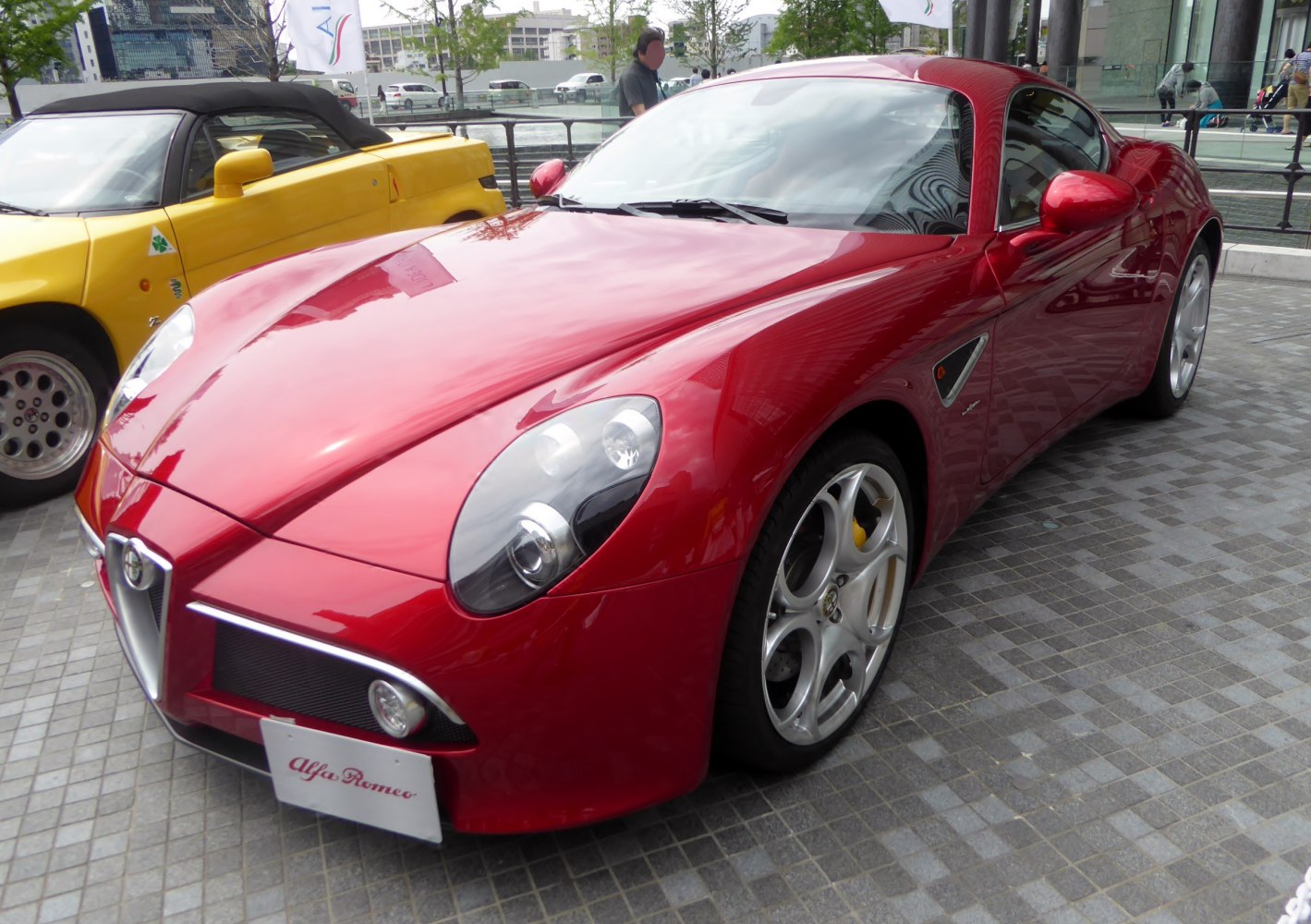 Red sports coupe with sleek design, distinctive headlights, and alloy wheels