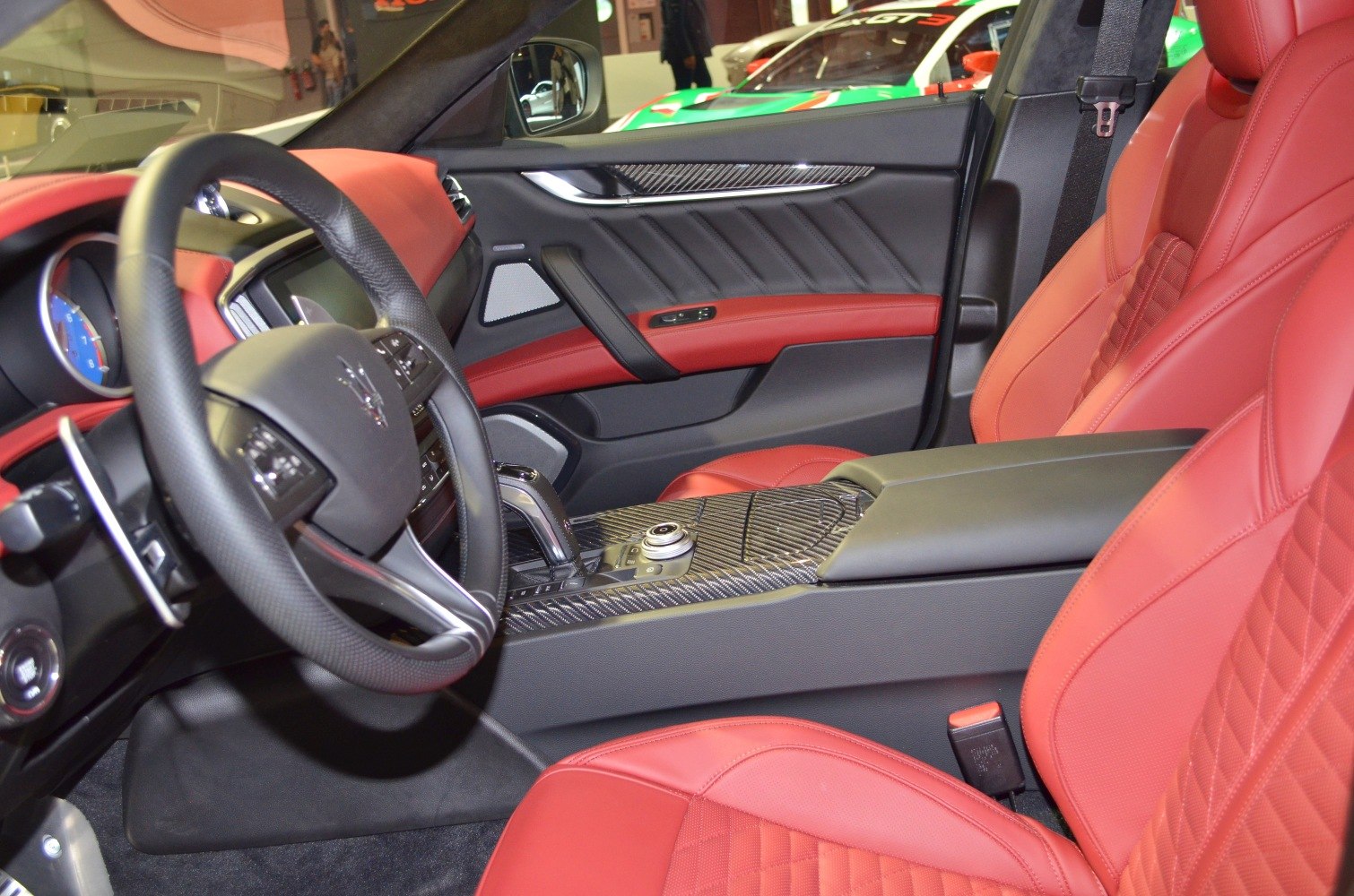 Red leather seats and carbon fiber center console in luxury car interior.