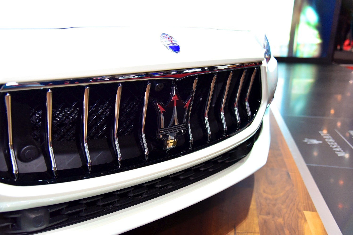 Close-up of a luxury car front grille with vertical chrome slats and central emblem.