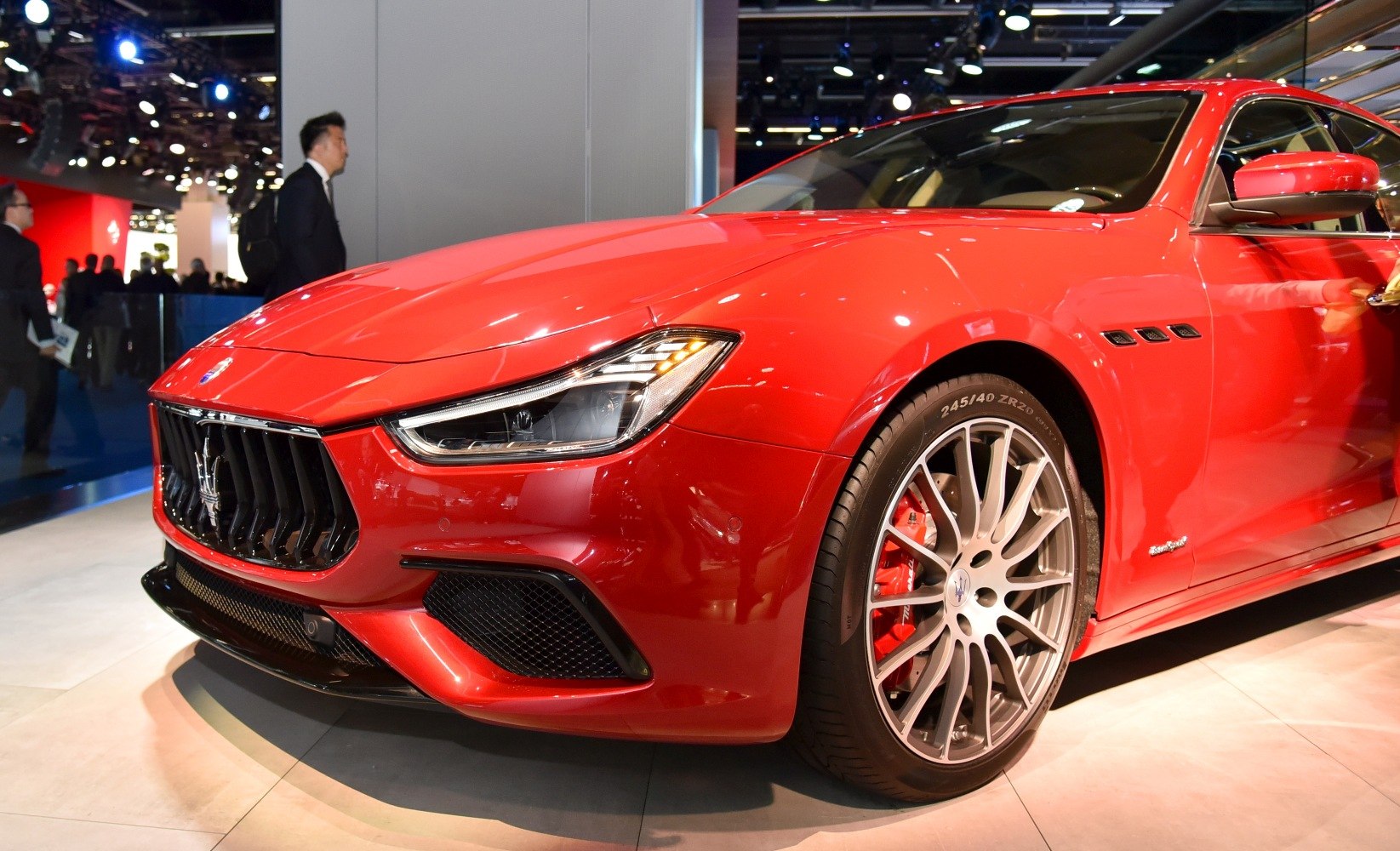 Close-up of aggressive front grille with sleek headlight and alloy wheel with red brake calipers