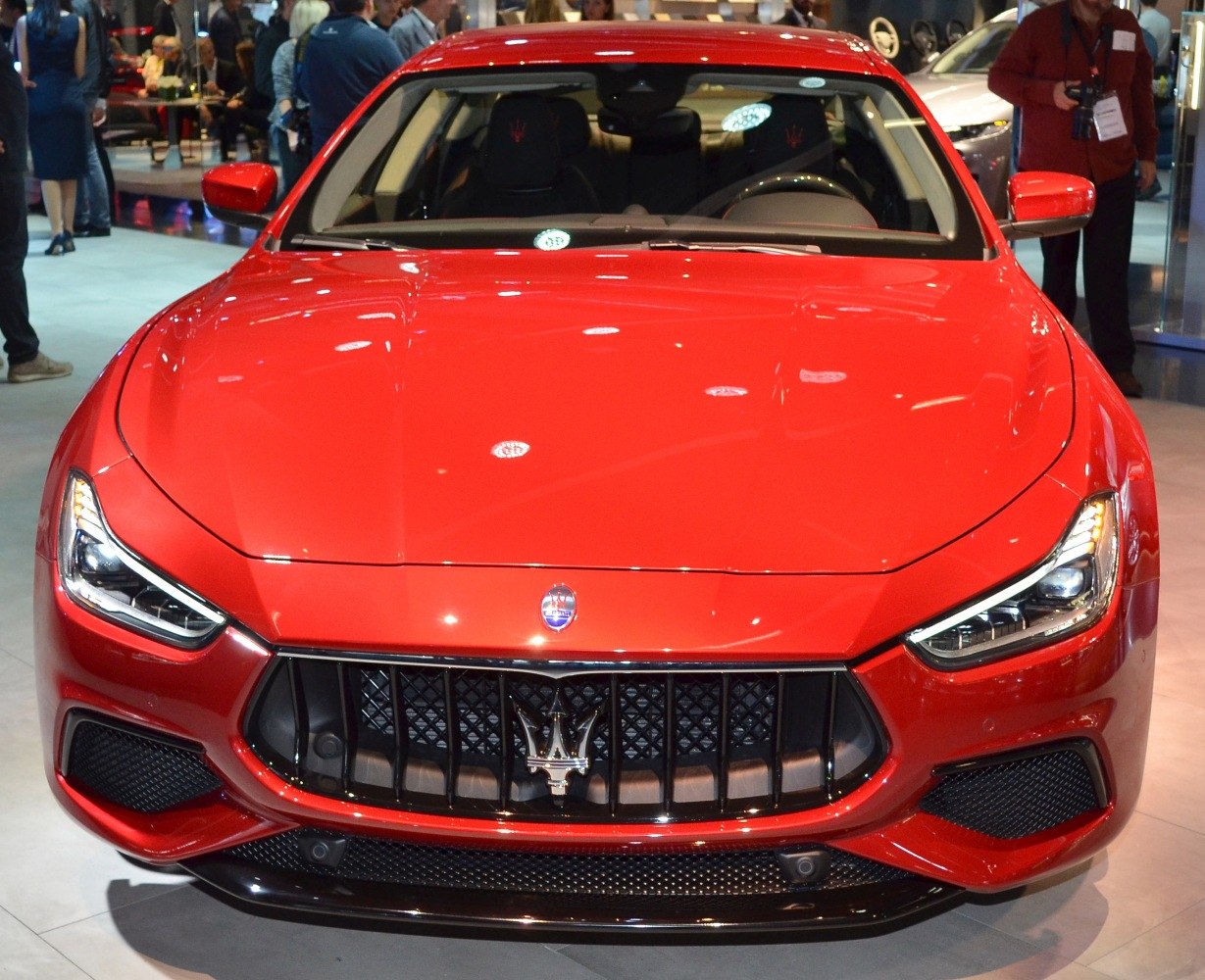 Bright red luxury sedan front with signature grille and aggressive headlights