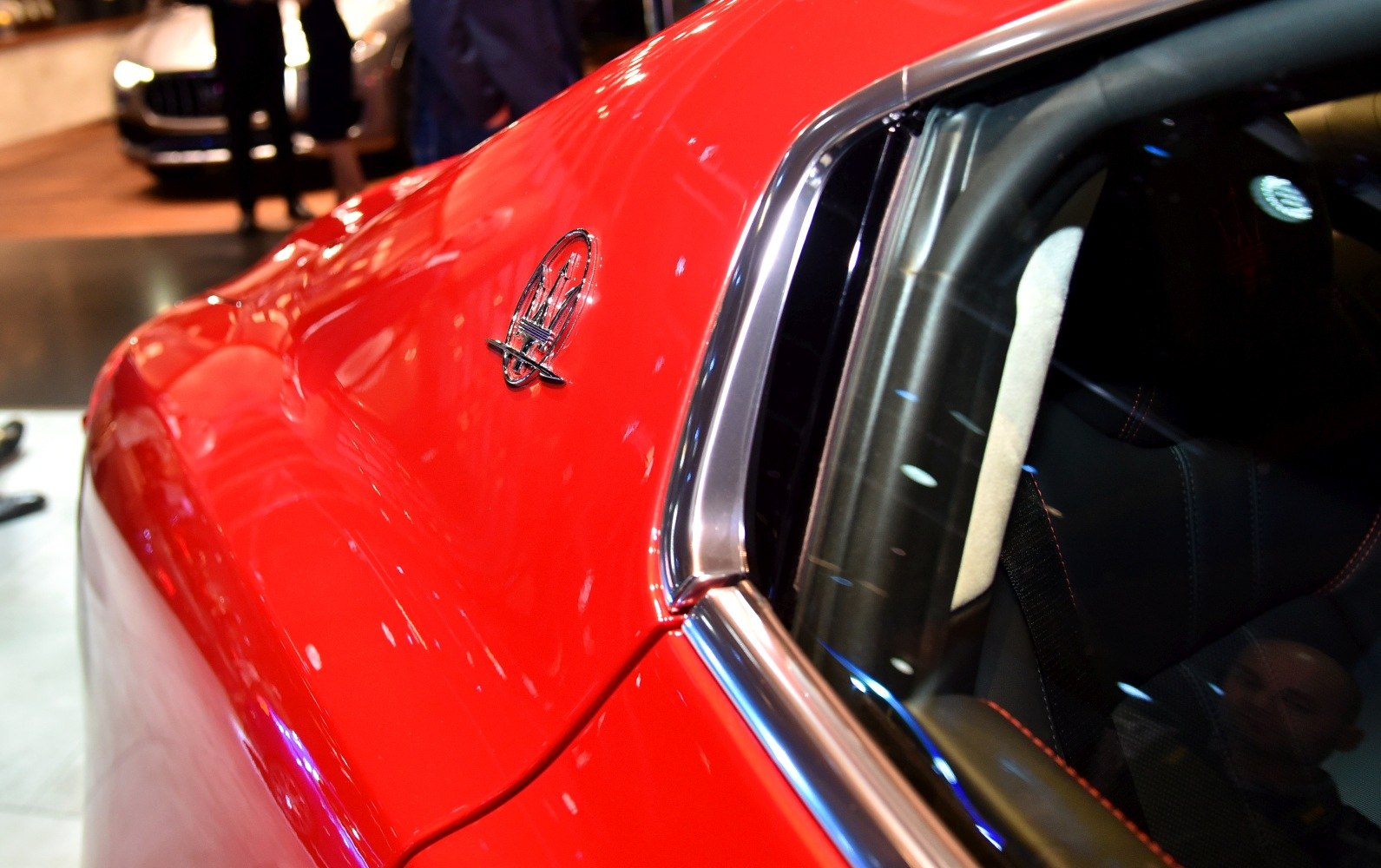 Red sports car side panel with emblem and chrome window trim