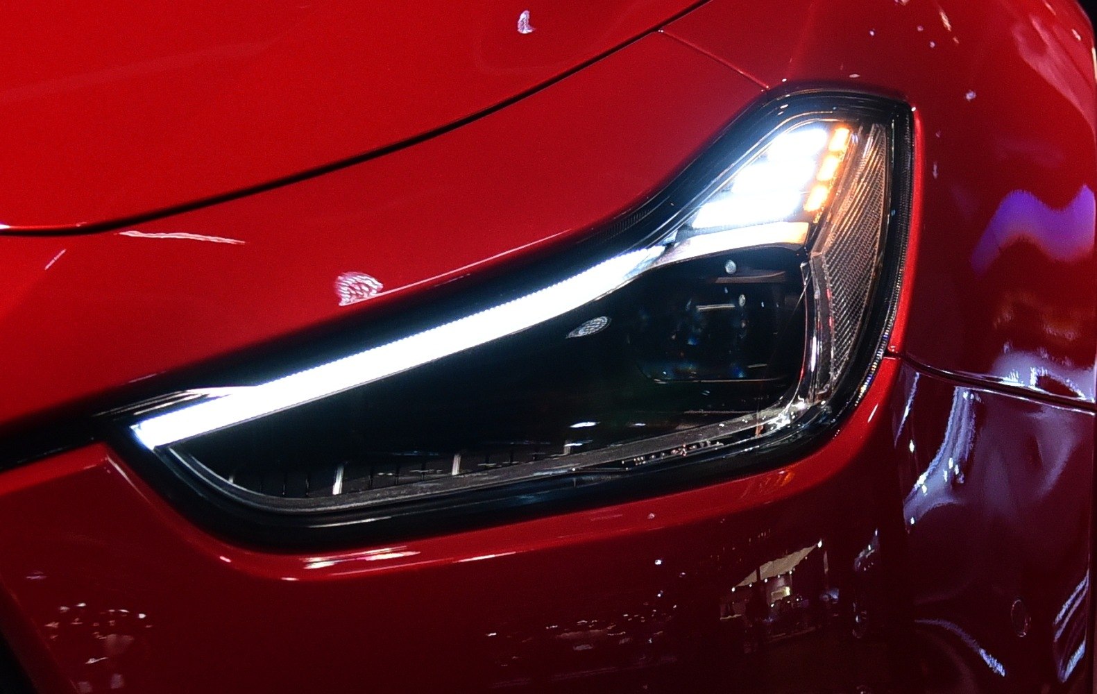 Close-up of LED headlight with red glossy body panel