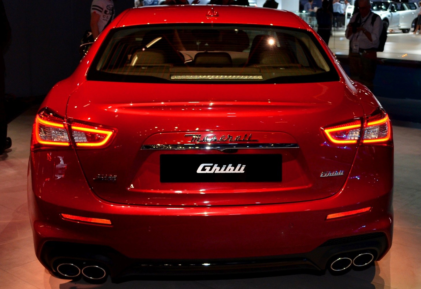 Rear LED tail lights and quad exhaust of a luxury sedan.