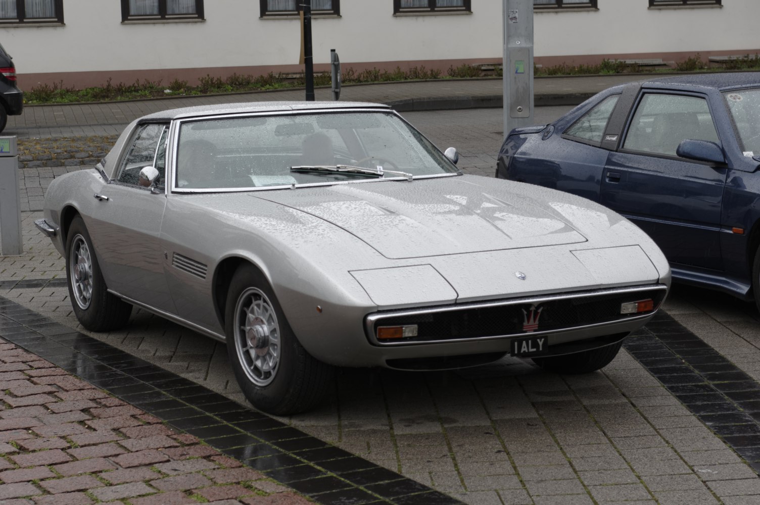 Vintage sports coupe front and wheel design with silver body and sleek lines.