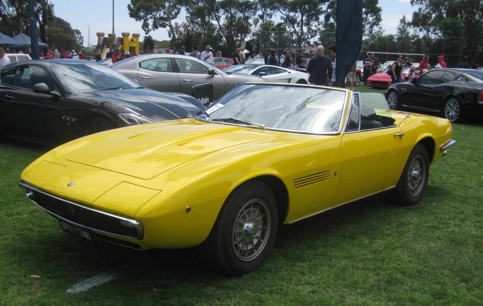 Yellow convertible sports car with sleek aerodynamic body and classic alloy wheels.