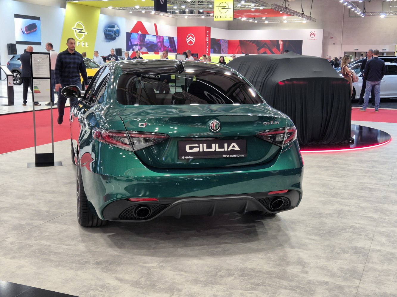 Rear view of a green sedan with distinctive tail lights and dual exhaust.
