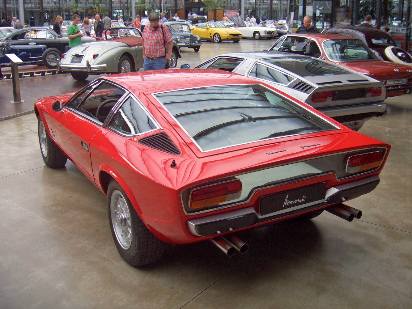 Red sports car rear with dual exhaust pipes and large rear window