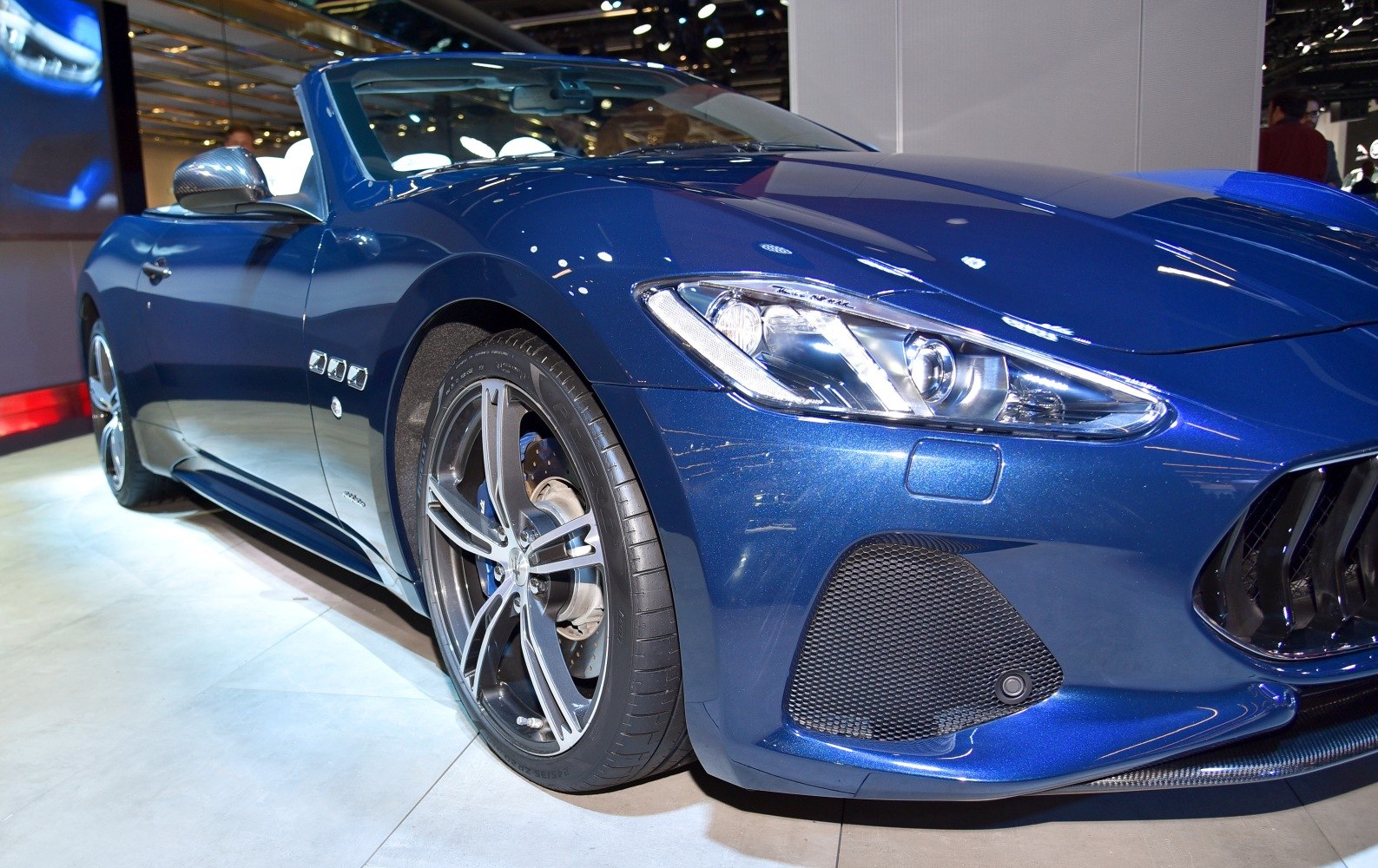 Front side view showing headlight and alloy wheel of blue luxury convertible