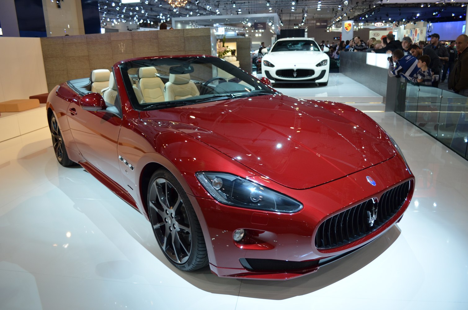 Red convertible with open roof, black rims, and luxury beige interior.