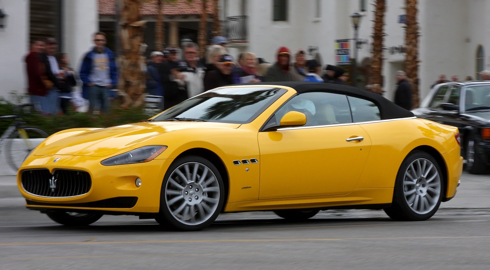 Yellow convertible sports coupe with black soft top and alloy wheels