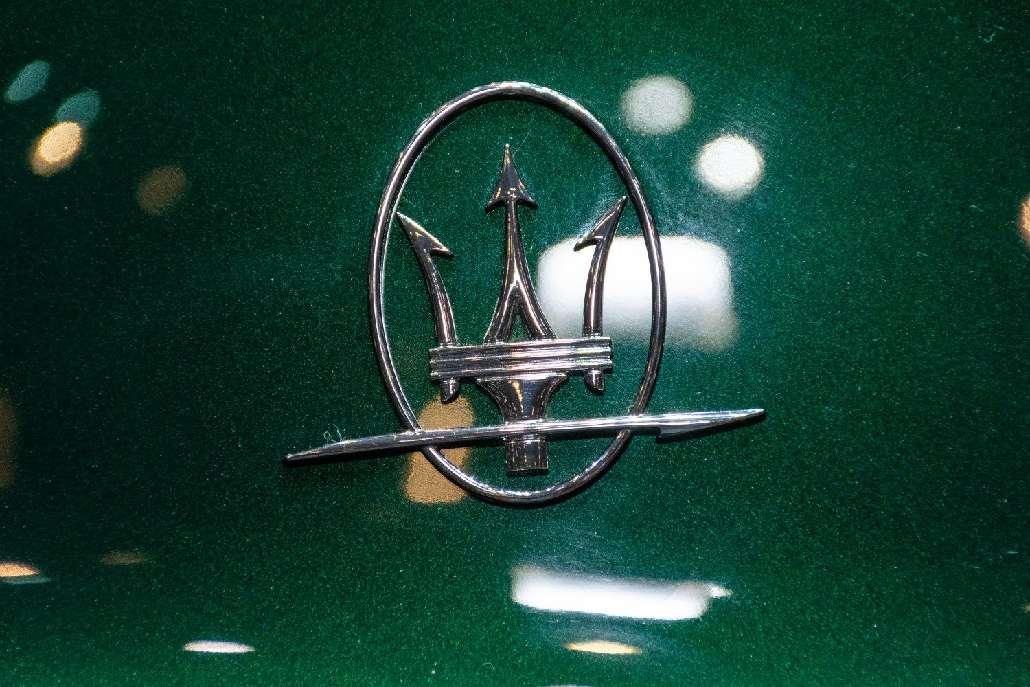Close-up of a chrome trident emblem on a green metallic surface
