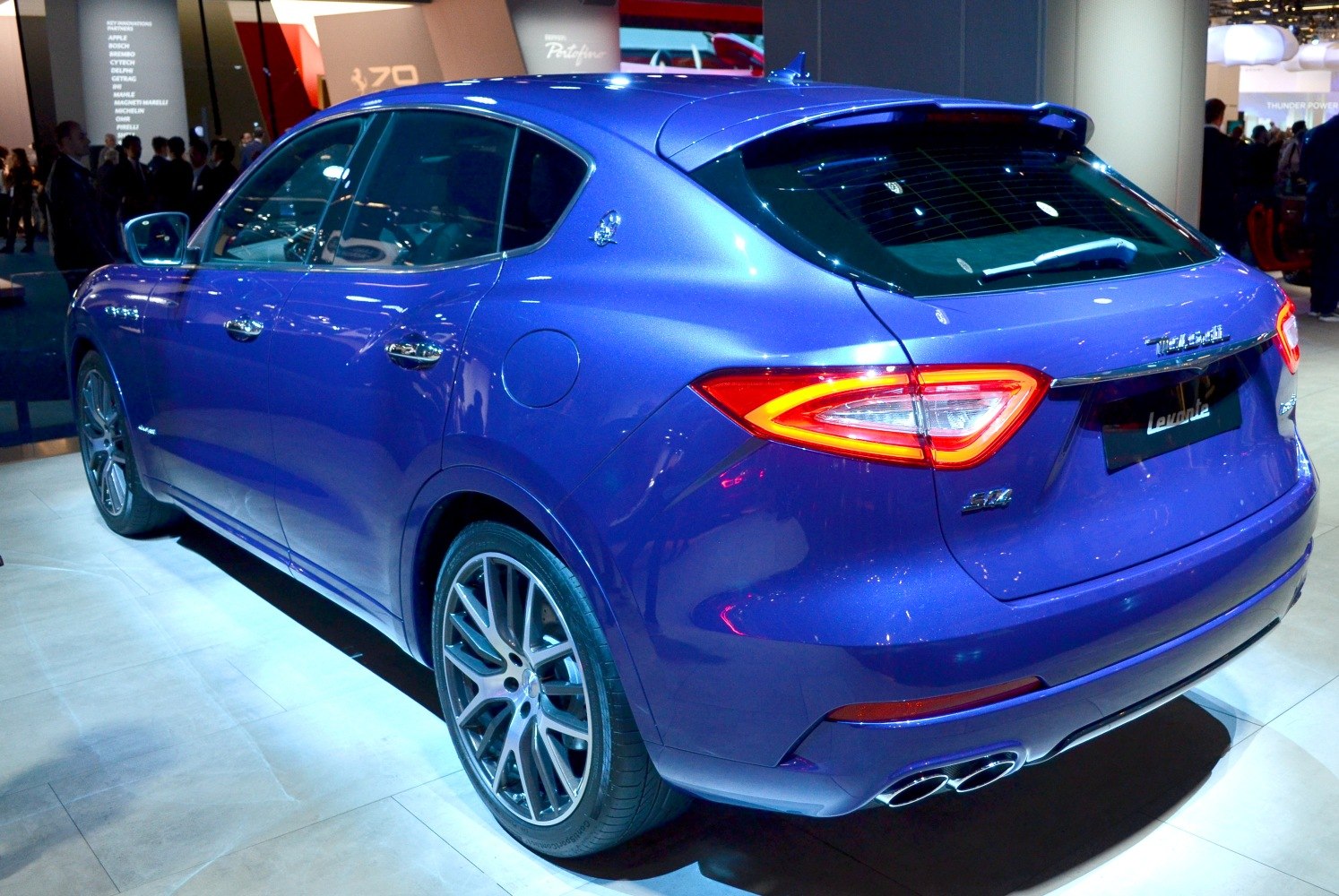 Rear side view of blue SUV with illuminated tail lights and dual exhausts