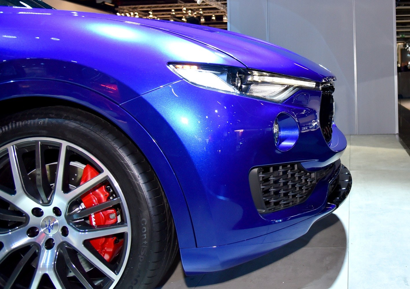 Front wheel, red brake caliper, and LED headlight detail