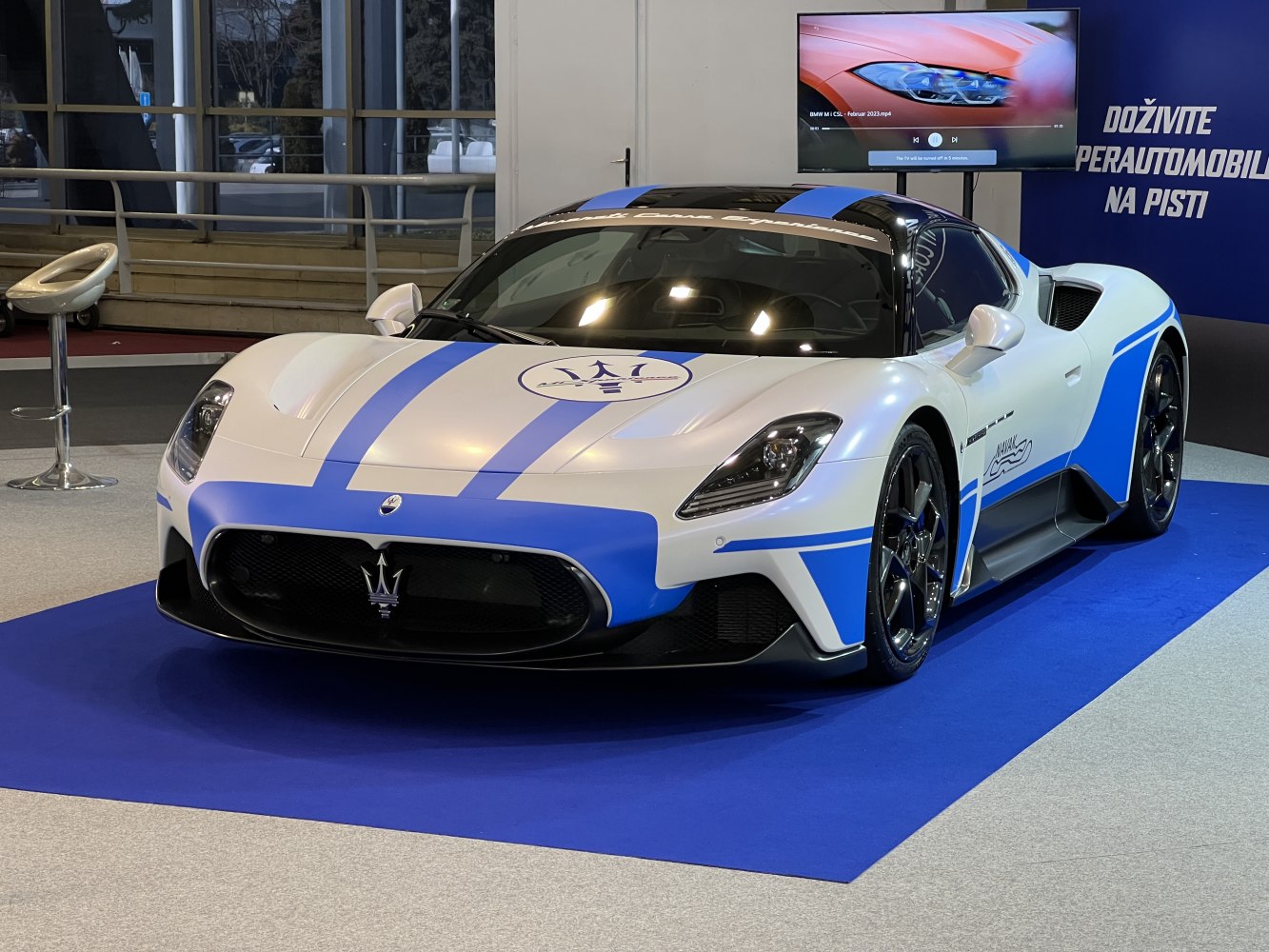 White sports coupe with blue racing stripes and aggressive front design