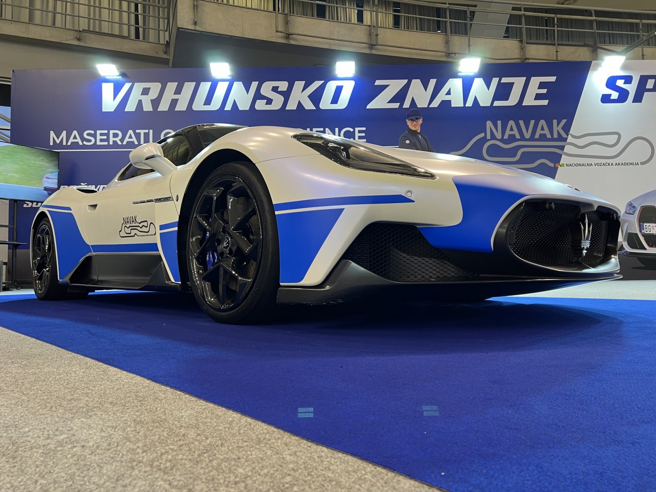 Front low-angle view of white and blue racing car with black wheels
