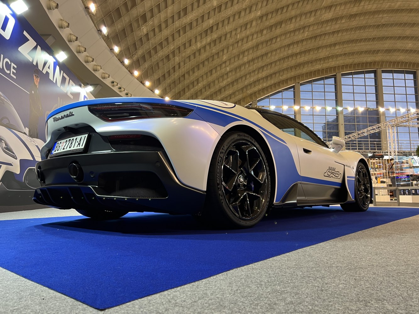 Low rear and side view of sports coupe with blue and white racing livery and black alloy wheels