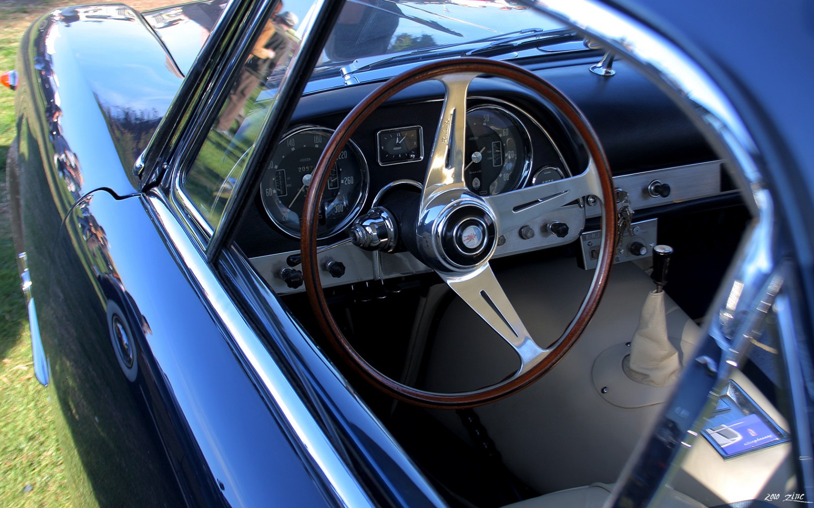 Classic wooden steering wheel with vintage instrument cluster and manual gear shift.