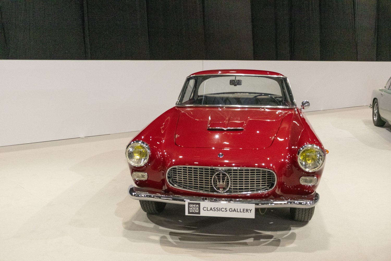 Front view of a red vintage sports car with chrome grille and yellow round headlights.