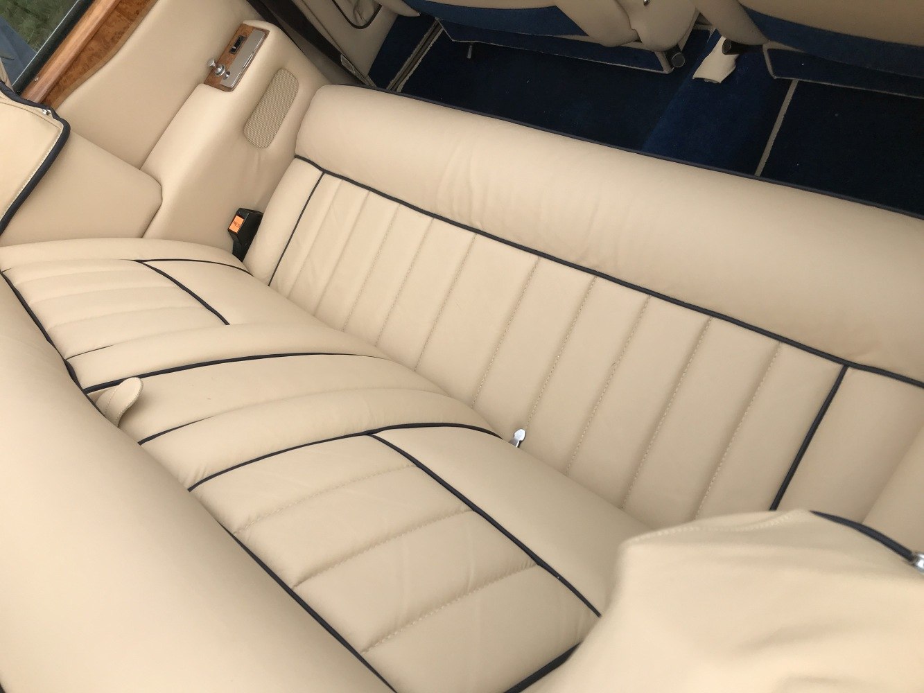 Beige leather rear seat with black piping and wood trim