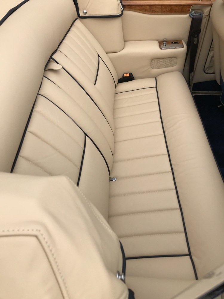 Beige leather rear seat with black piping and wood trim
