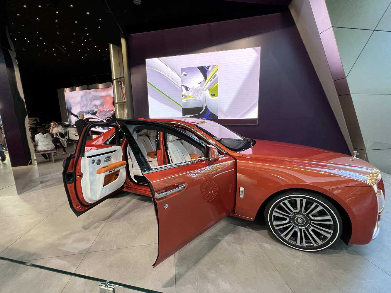 Luxury sedan with rear-hinged doors and white leather interior with orange accents