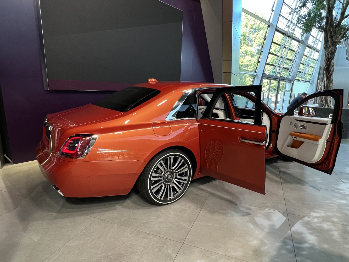Luxury sedan rear view with open doors and stylish alloy wheels.