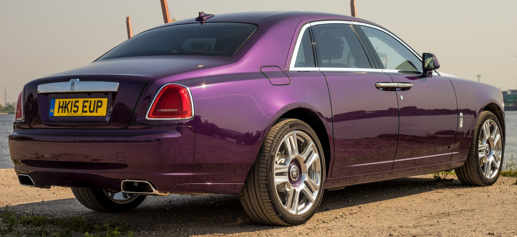 Rear side view of purple luxury sedan with dual exhaust and chrome trim.