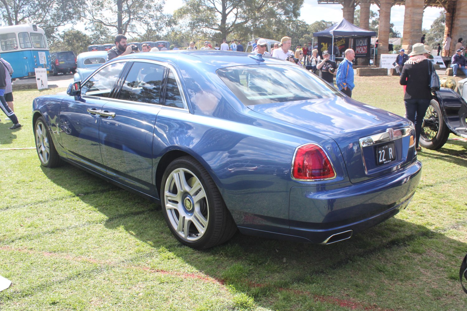 Blue luxury sedan rear side view with alloy wheels and taillights