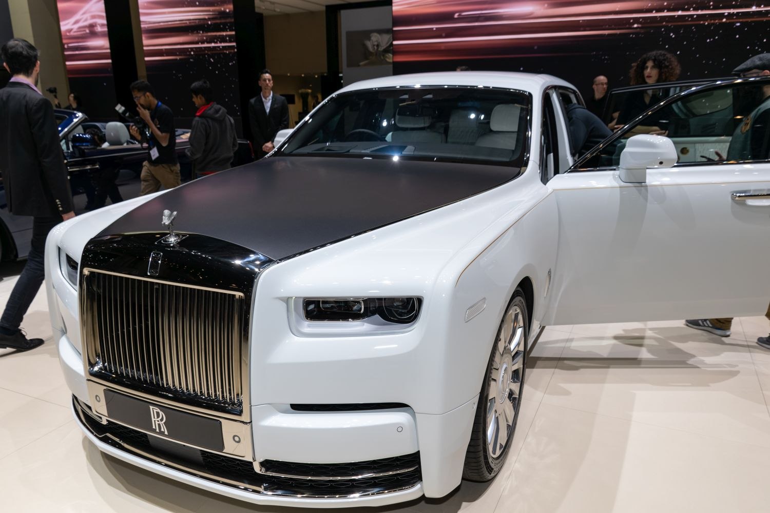 White luxury sedan with matte black hood and large chrome grille