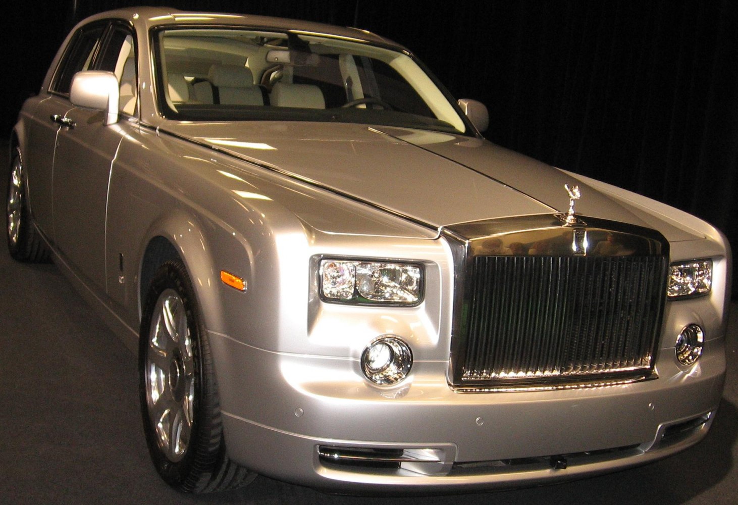 Silver luxury sedan front with vertical grille and hood ornament