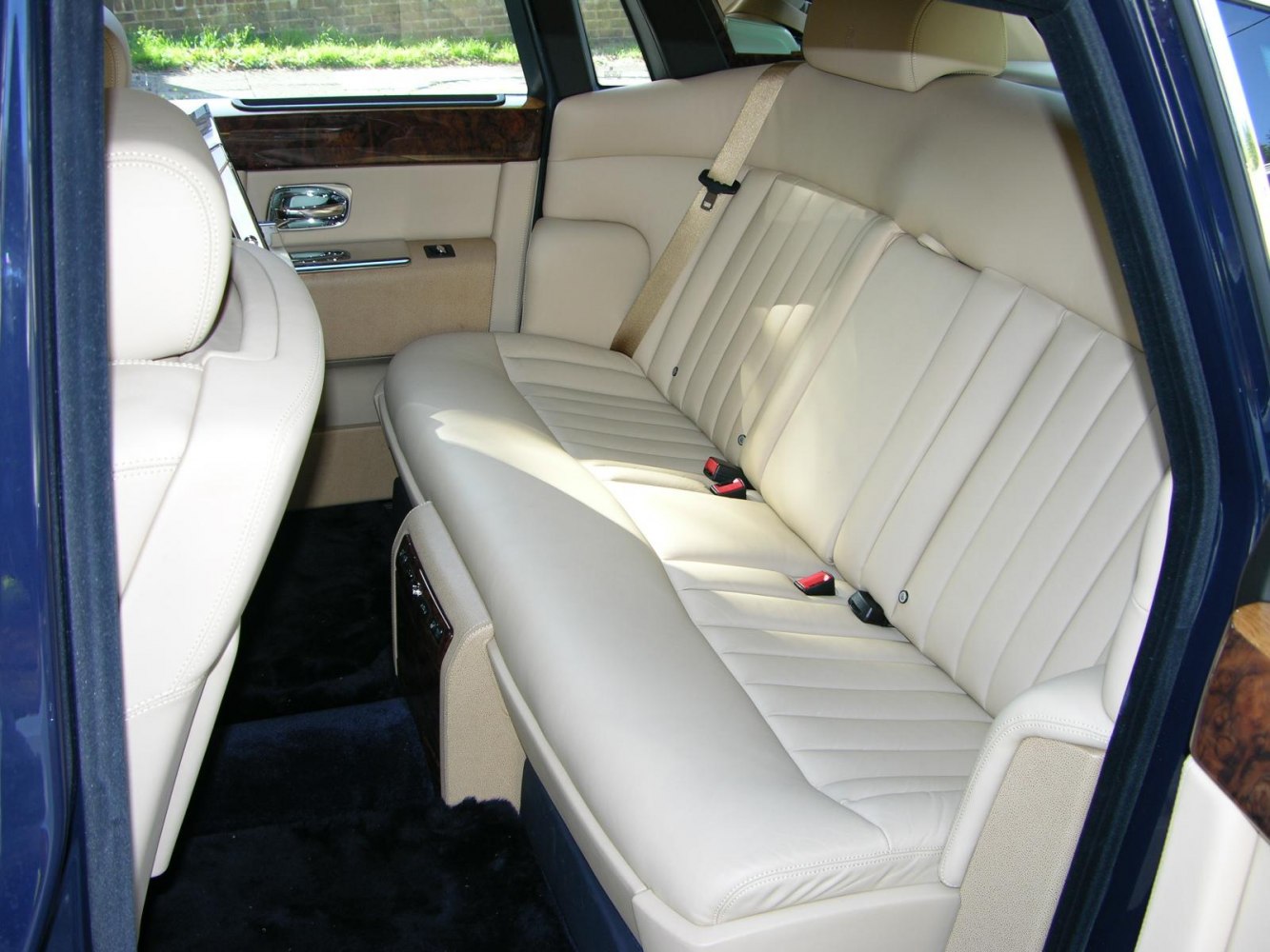 Plush beige leather rear seats with wood trim and seat belts