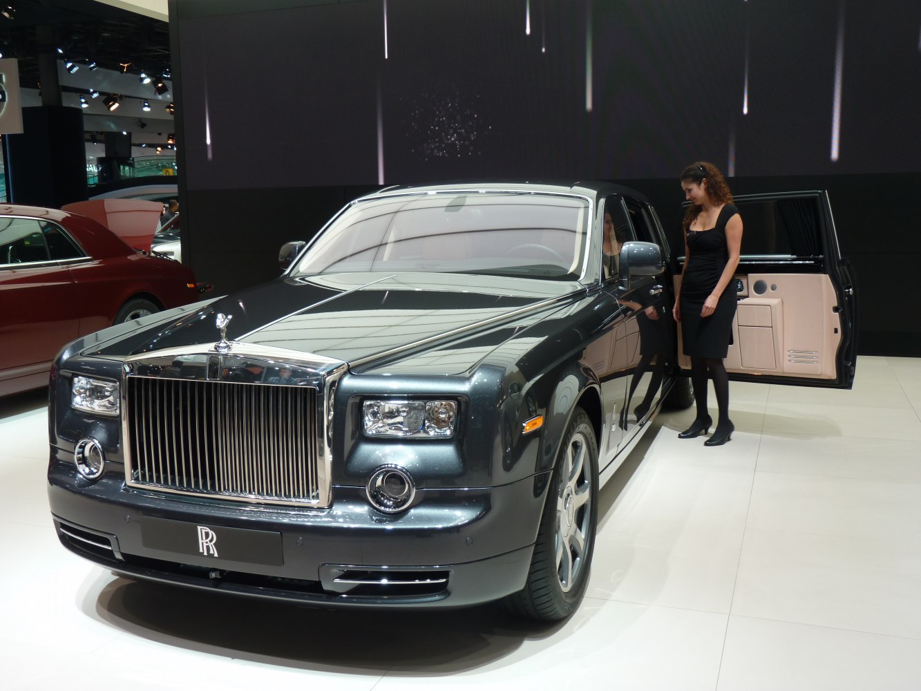 Luxury sedan front grille with open rear door.