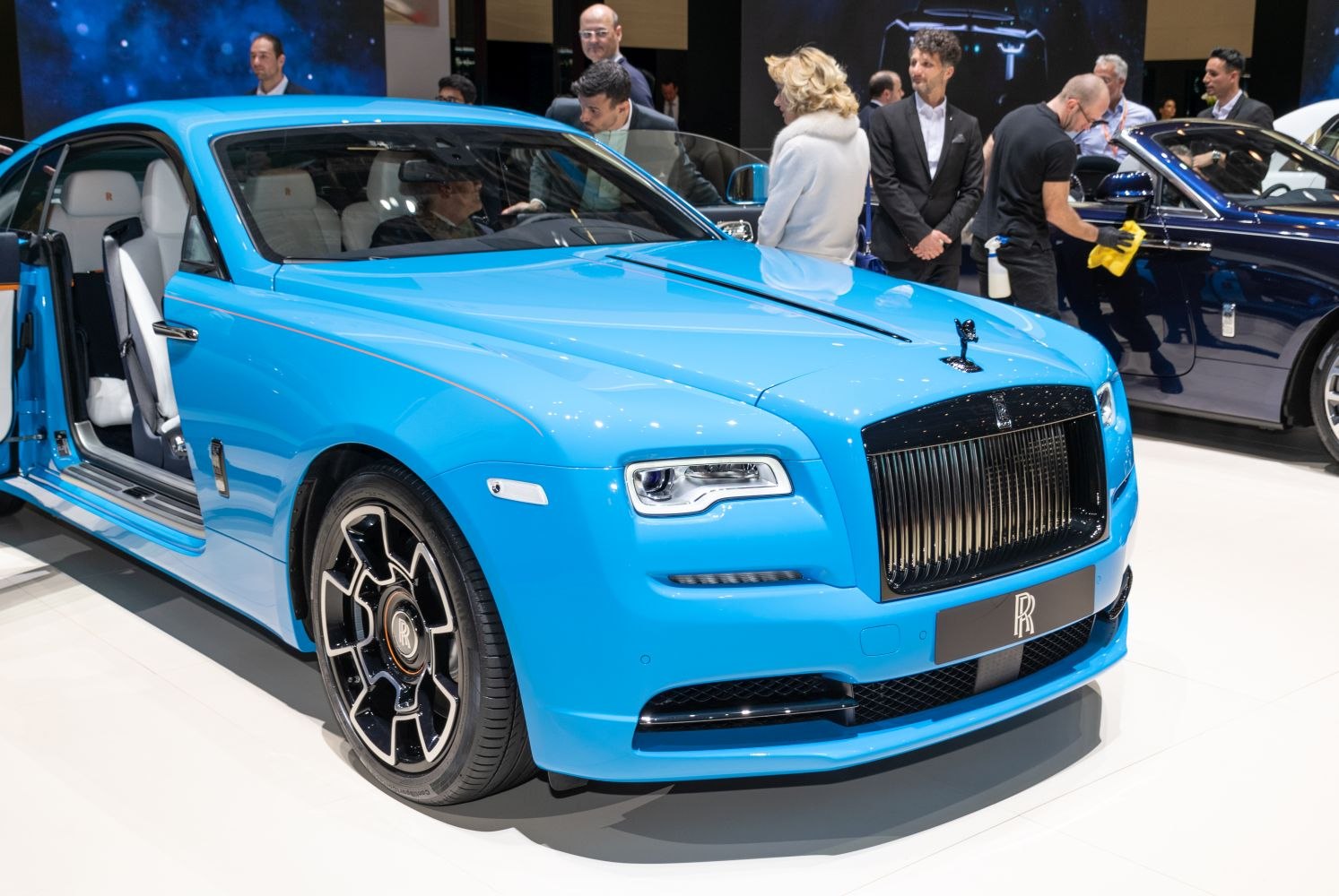 Blue luxury coupe with distinctive front grille and open door.