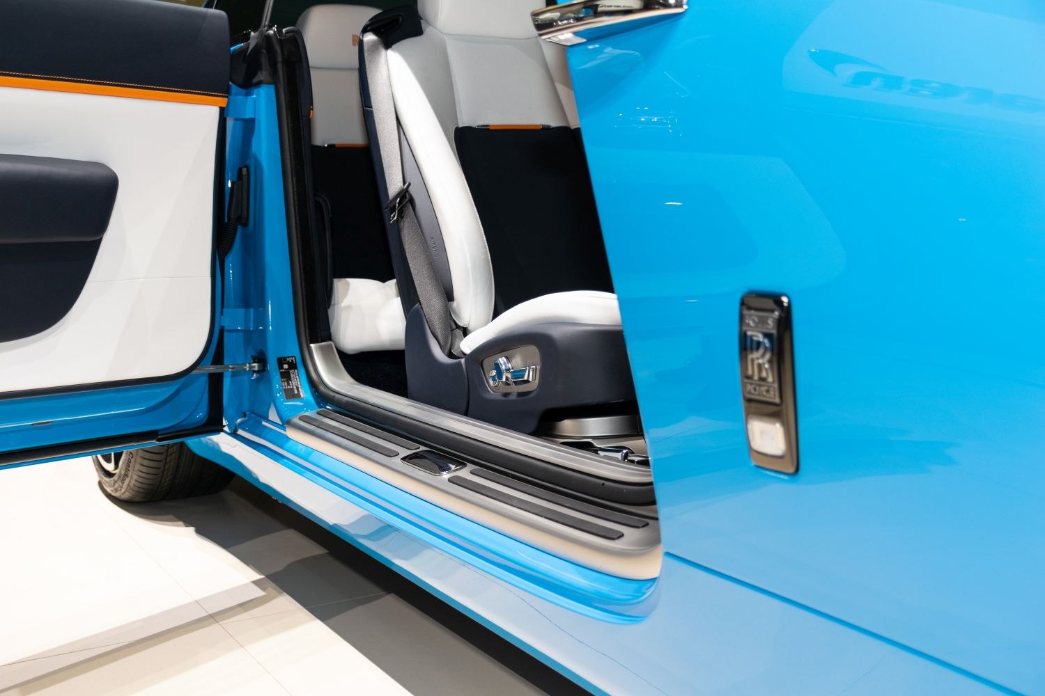 Opened car door with white luxury seats and blue exterior.