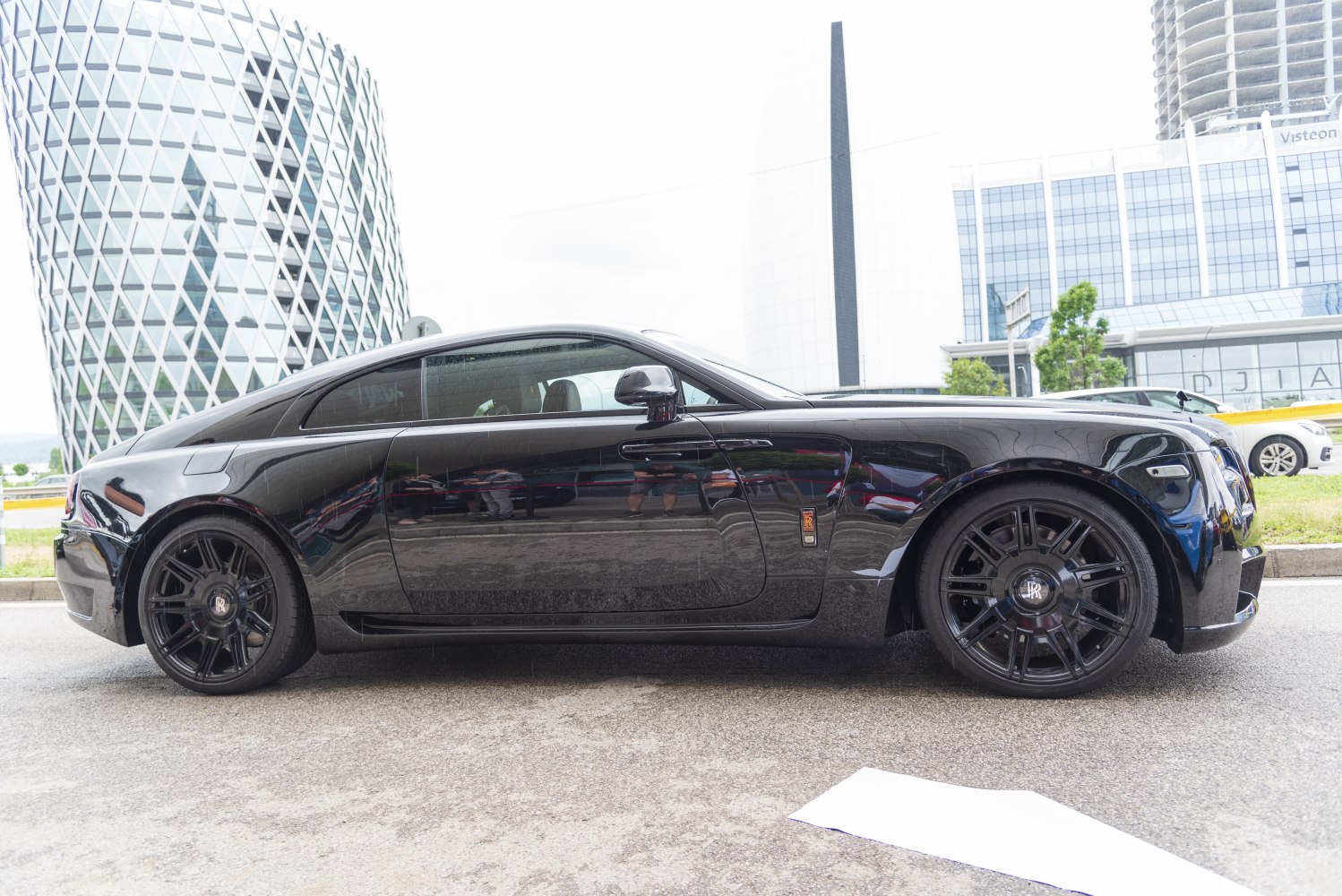 Side profile of sleek black luxury coupe with black alloy wheels