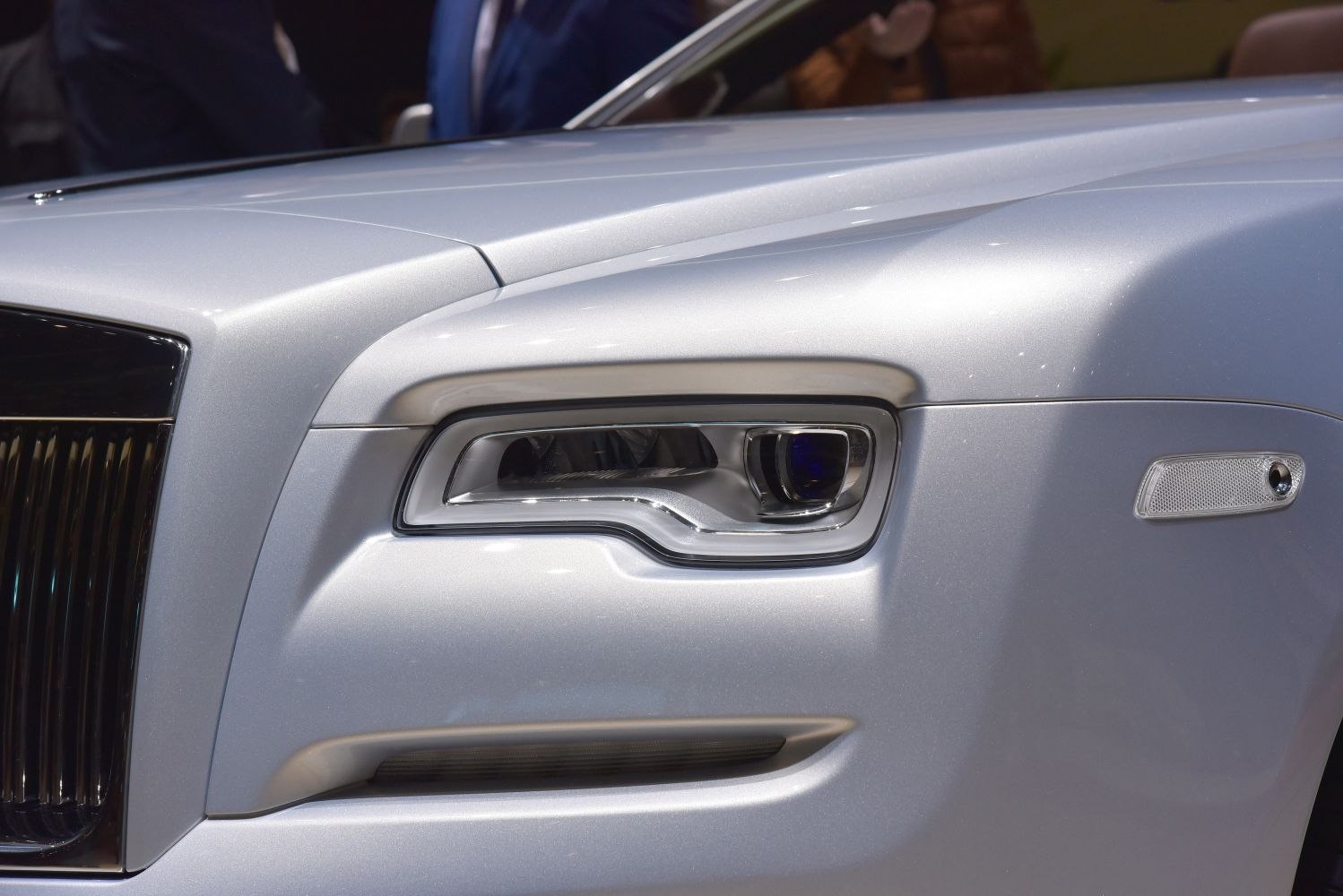 Front headlight and grille close-up in silver luxury car