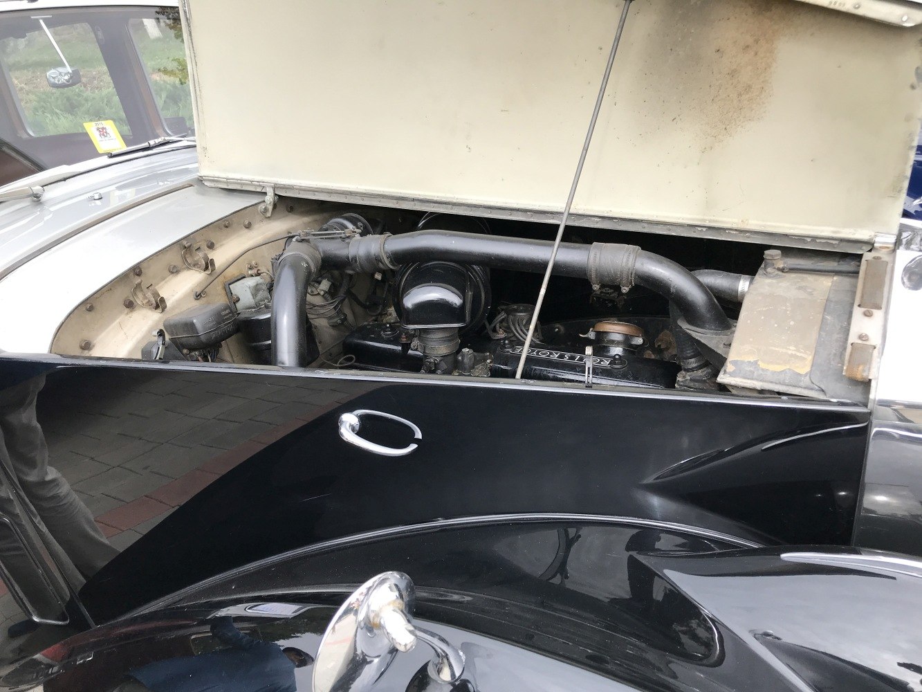 Vintage luxury car engine bay with detailed components and air intake pipes.