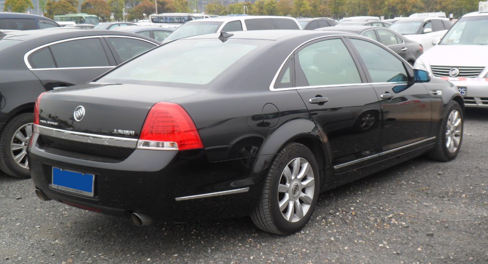 Rear and side profile of a black luxury sedan with smooth curves and chrome trim.