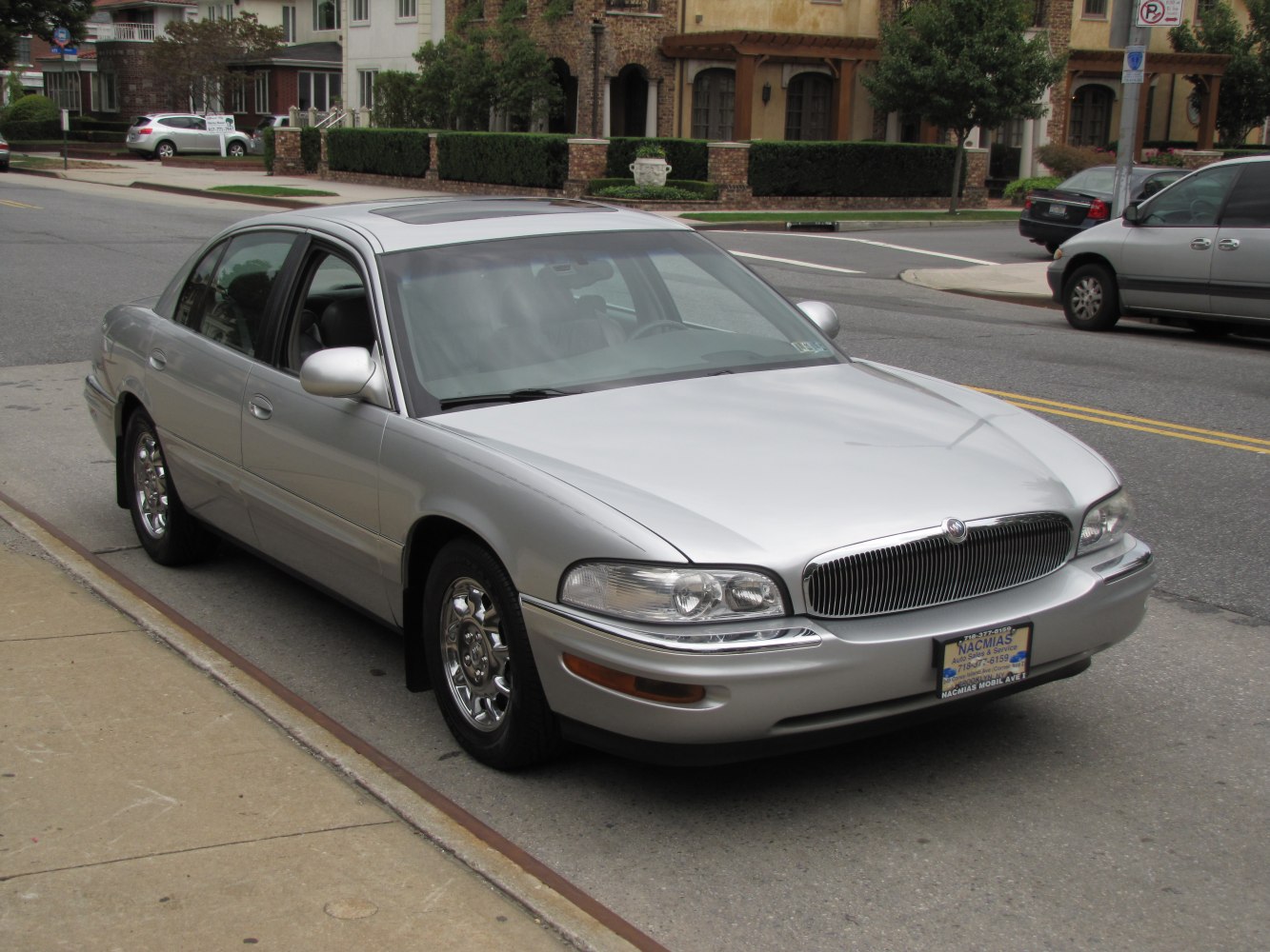 Front side view of silver sedan with chrome wheels and distinct grille